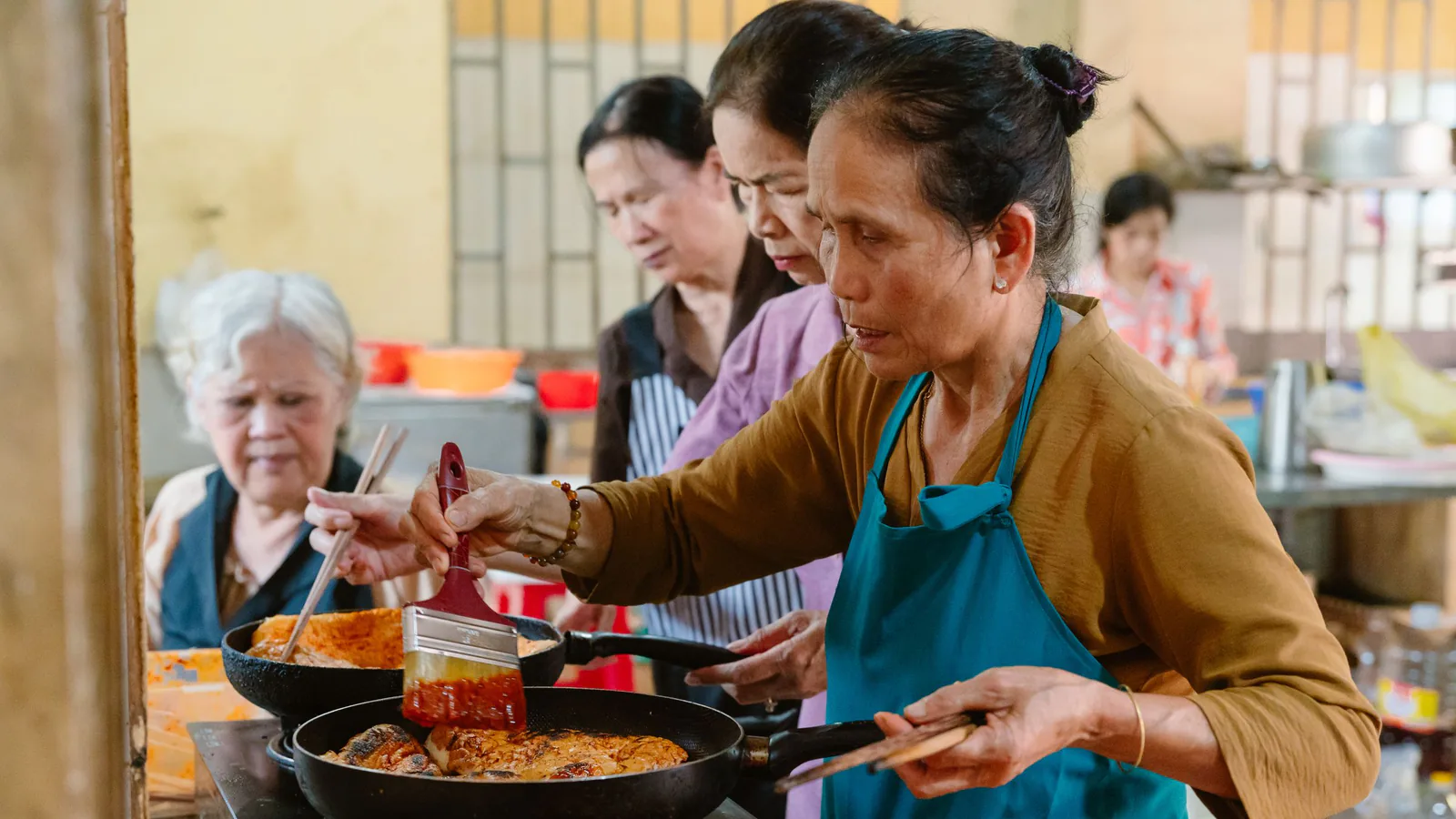 Apetit'Oh, la escuela de cocina experiencial de Madrid, se lanza a la franquicia | ZonaFranquicia Grupo diverso de mujeres cocinando juntas en una cocina moderna, en ambiente de aprendizaje colaborativo | ZonaFranquicia