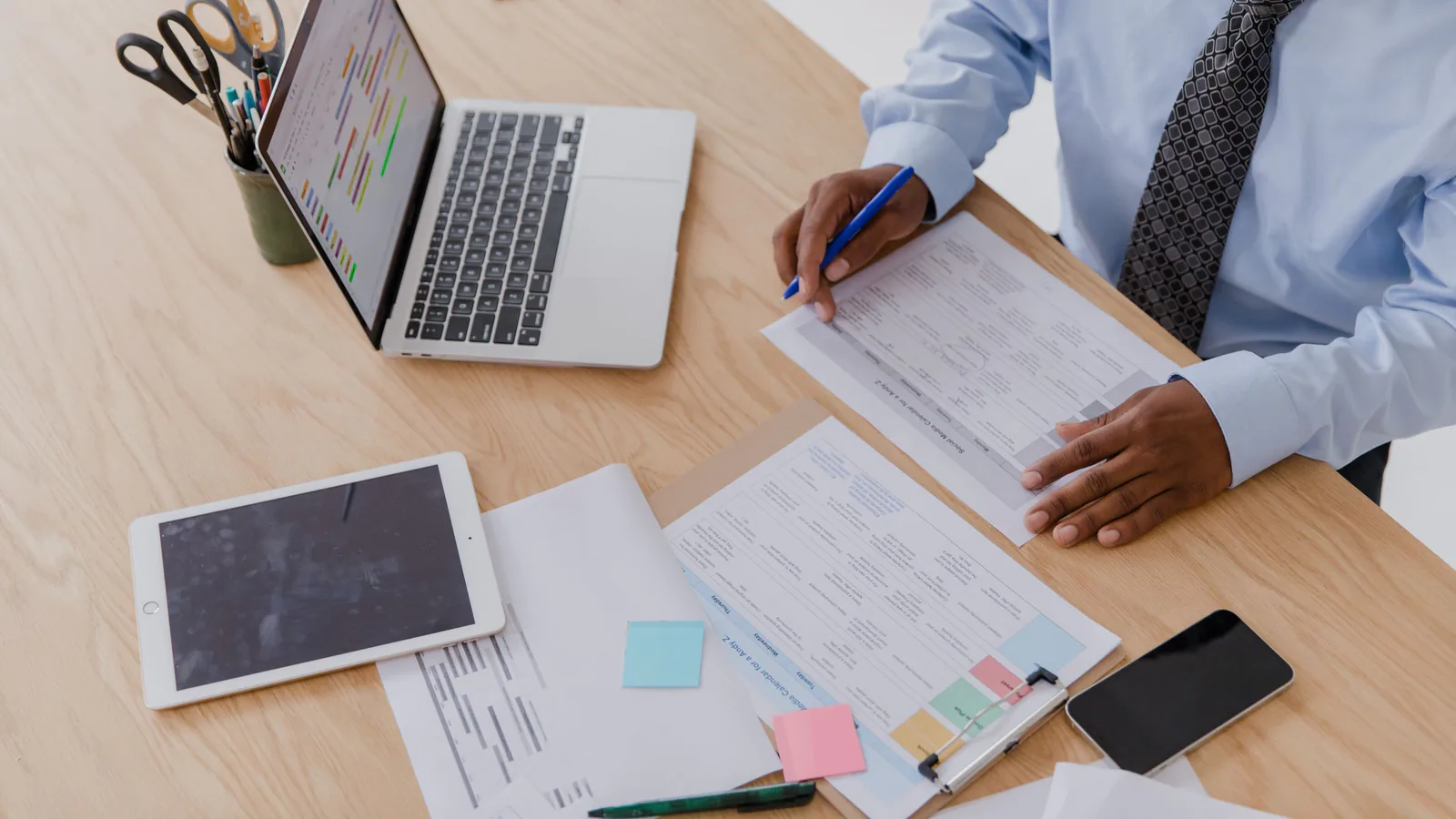 Auditoría de franquicia: qué revisar antes de invertir | ZonaFranquicia Empresario analizando documentos y datos en escritorio con laptop y tablet desde vista superior | ZonaFranquicia