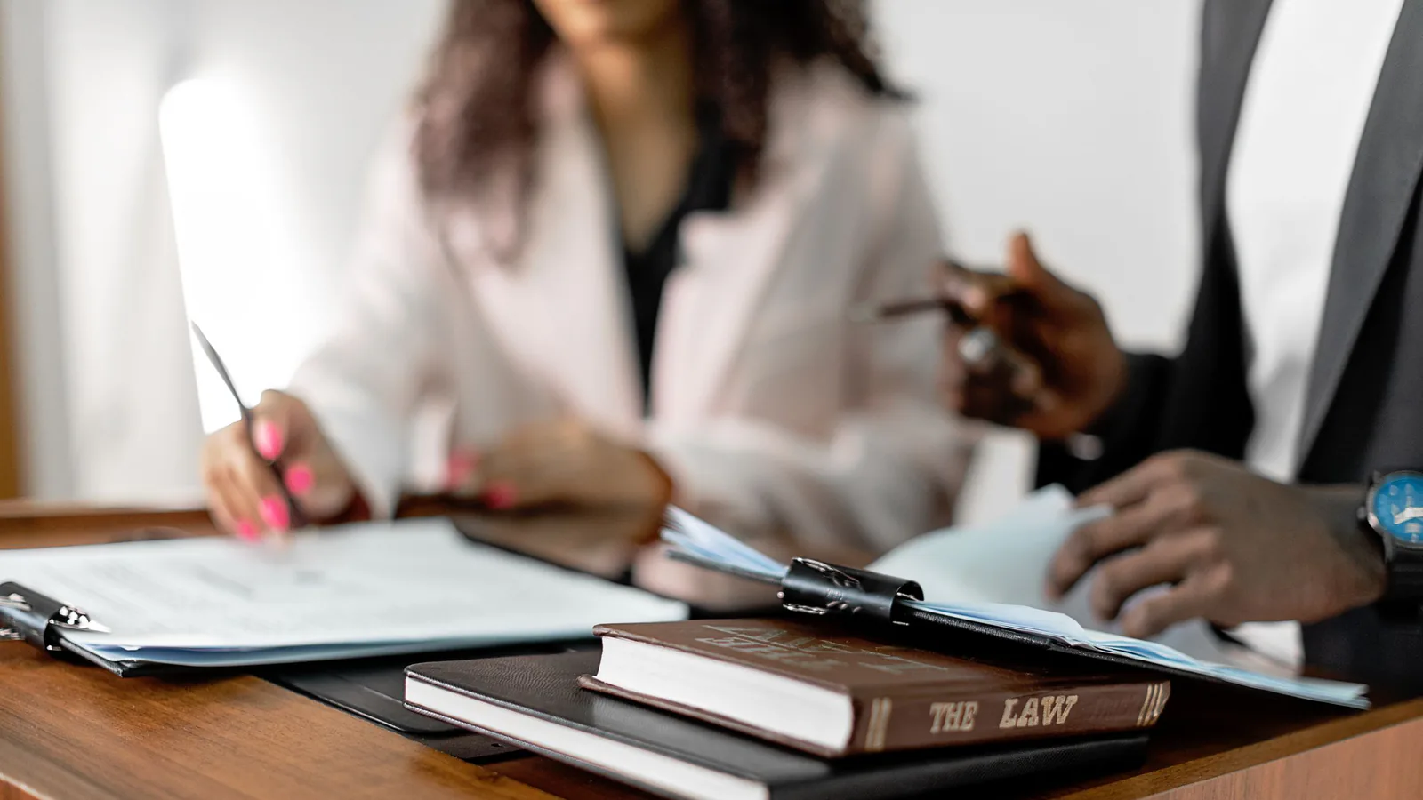 Dos abogados revisando documentos legales en un escritorio con libros de derecho, ambiente profesional | ZonaFranquicia
