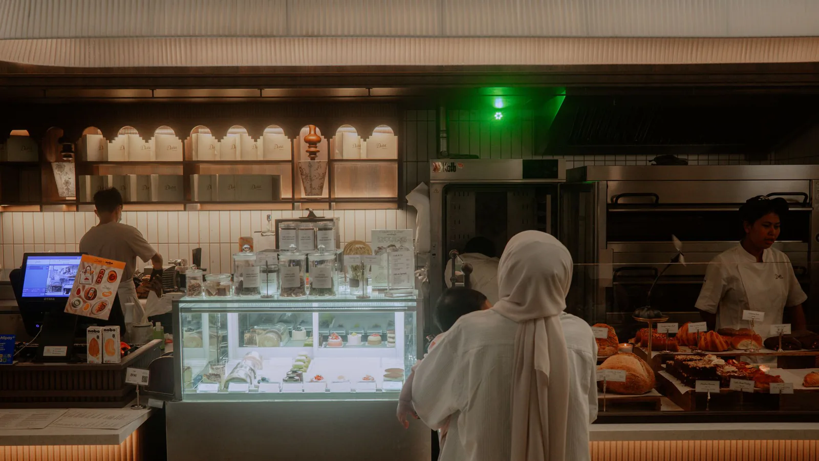 Interior cálido de panadería con clientes y personal preparando pedidos entre vitrinas de productos frescos | ZonaFranquicia