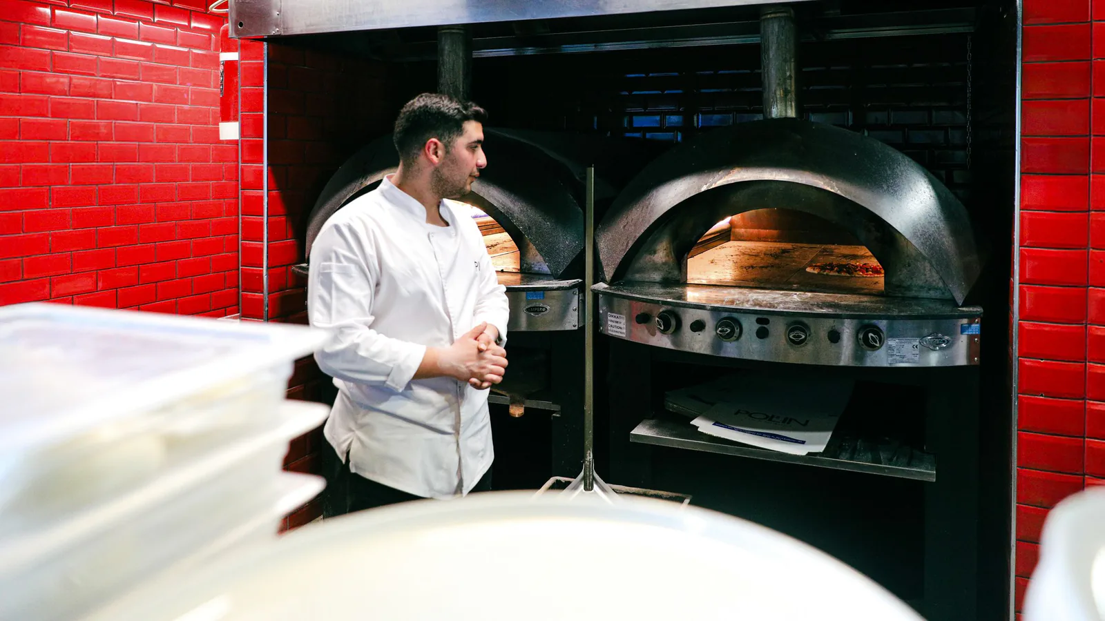 Domino's Pizza pisa el acelerador en España: dos nuevas aperturas y un modelo de franquicia que no… | ZonaFranquicia Chef en uniforme blanco junto a hornos de pizza en cocina de restaurante, listo para hornear | ZonaFranquicia
