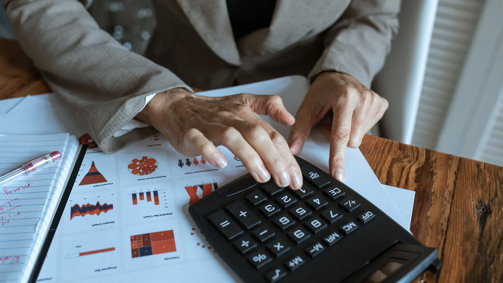 Franquicia vs. microempresa: cuál es más rentable en 5 años | ZonaFranquicia Empresario analizando gráficos financieros y utilizando calculadora en su escritorio de oficina | ZonaFranquicia