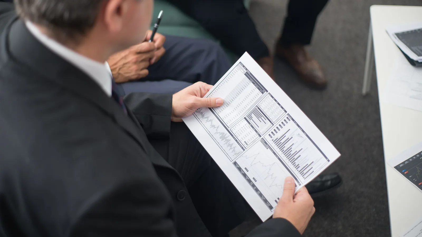 Franquicia vs. representante: cuál genera más ingresos | ZonaFranquicia Dos empresarios analizan documentos financieros durante una reunión de negocios en oficina | ZonaFranquicia
