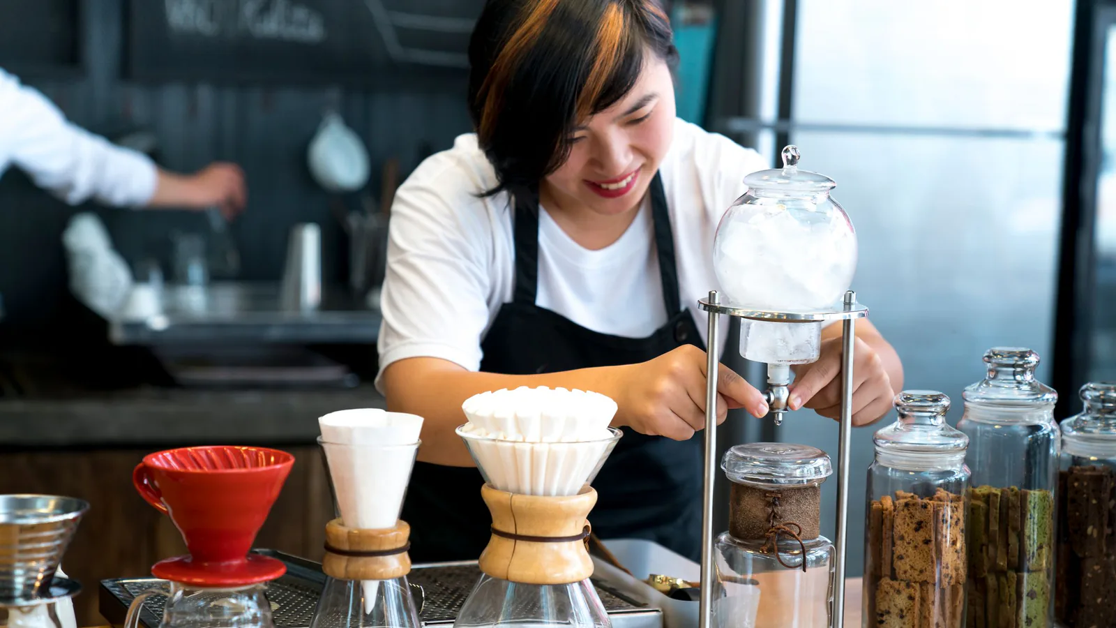 Barista sonriente preparando café con equipos modernos en una cafetería de estilo actual | ZonaFranquicia