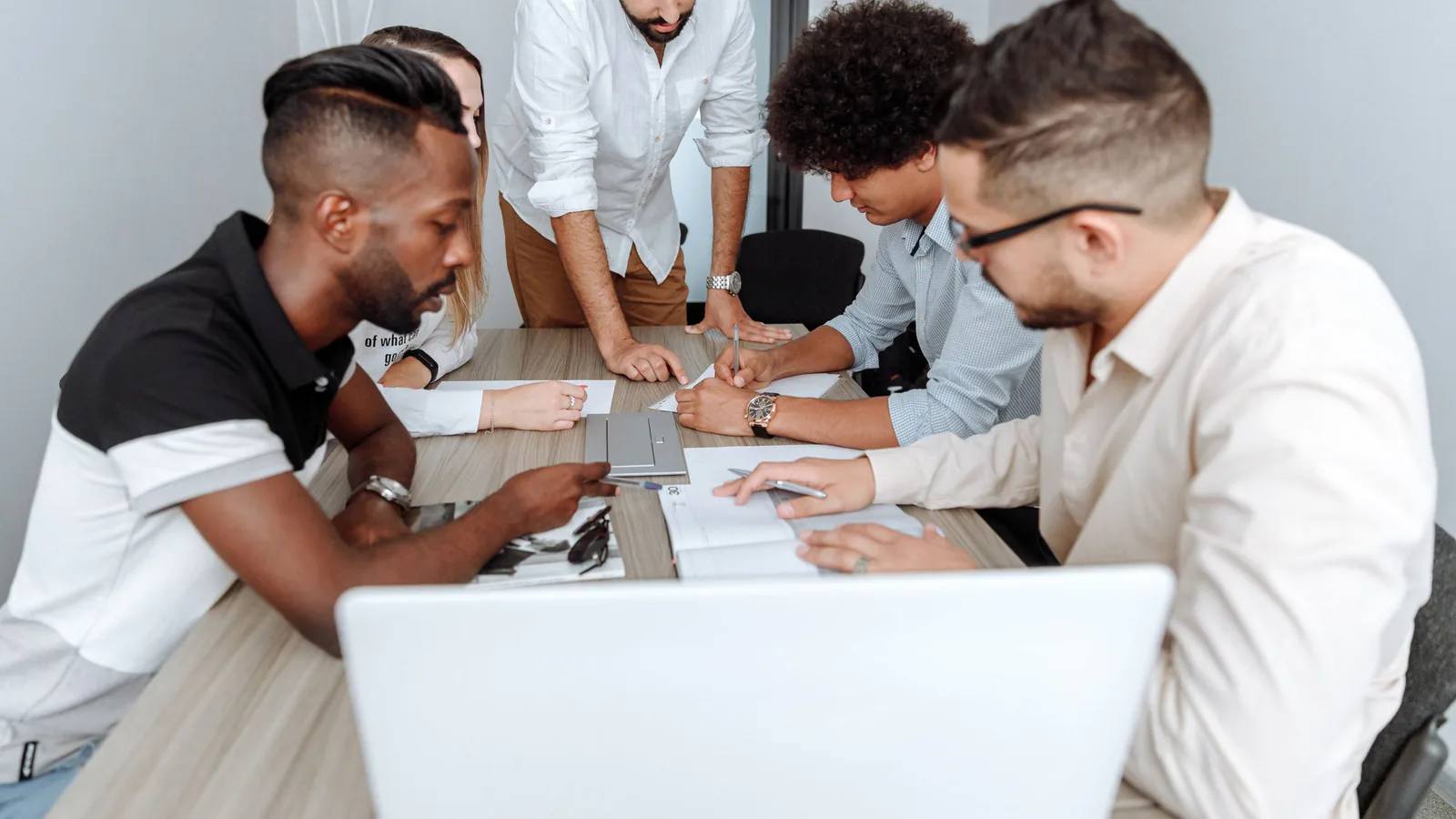 Gestiona el equipo de tu franquicia: salarios, motivación y retención | ZonaFranquicia Grupo diverso de profesionales colaborando alrededor de una mesa en reunión de negocios moderna | ZonaFranquicia