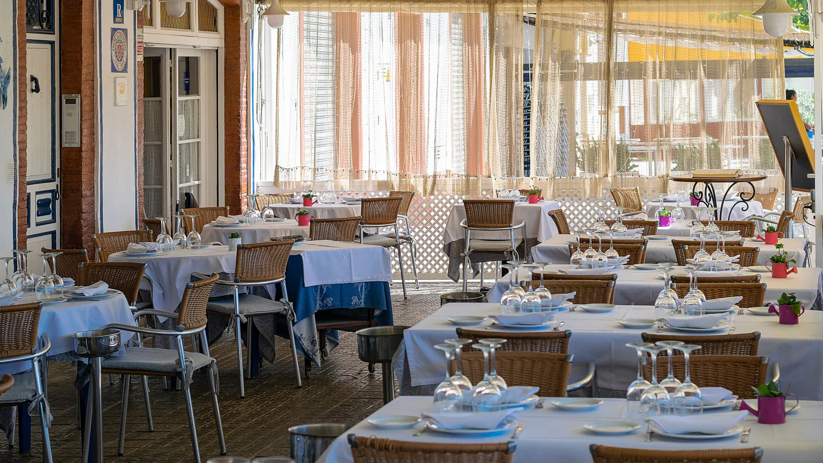 Grupo Saona pisa el acelerador: nuevas aperturas de franquiciados en Valencia, Alicante y Barcelona | ZonaFranquicia Terraza exterior de un restaurante mediterráneo con mesas vestidas bajo luz natural | ZonaFranquicia