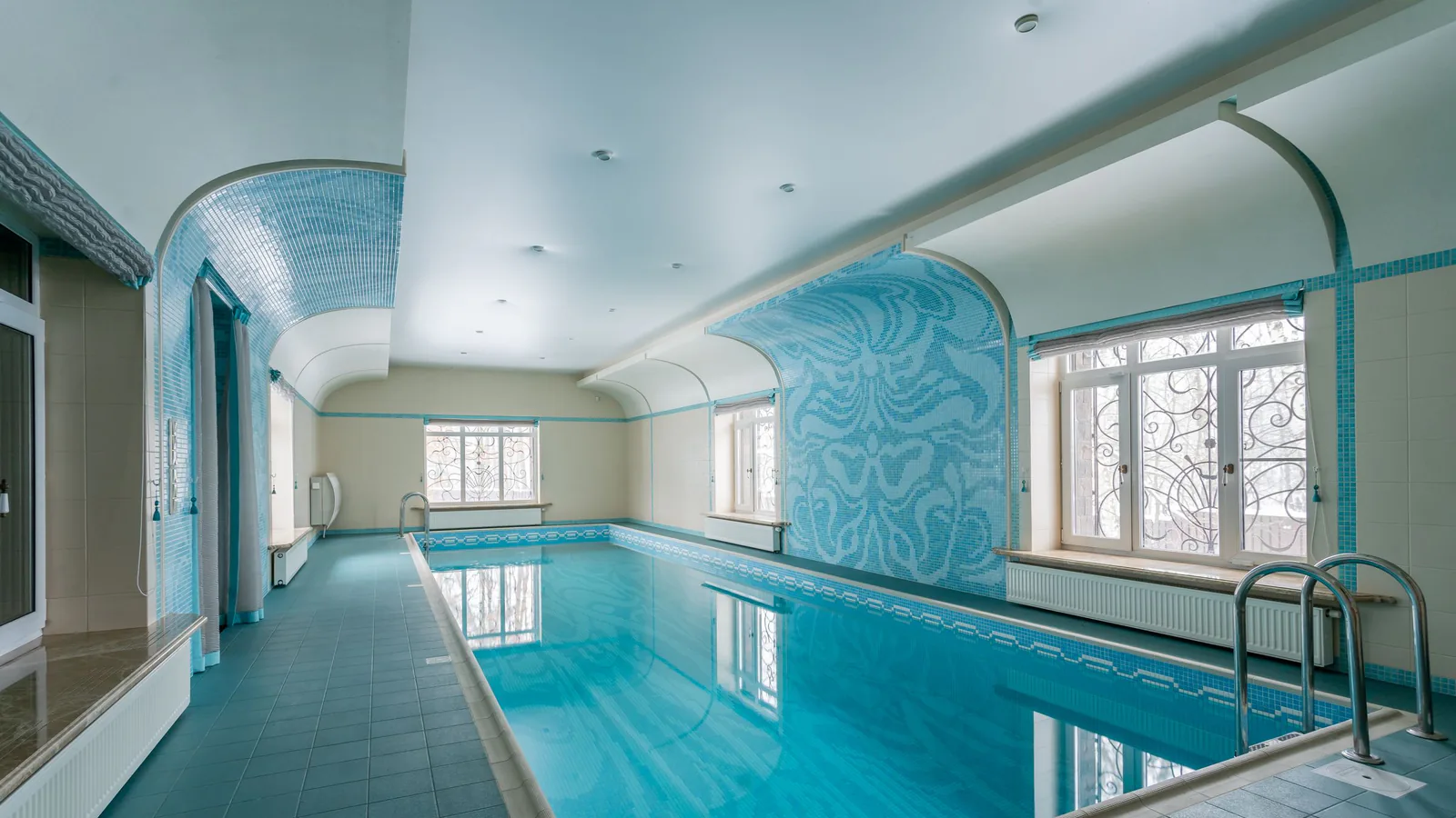 Piscina cubierta espaciosa con diseño moderno en azul y luz natural, equipada para uso profesional | ZonaFranquicia
