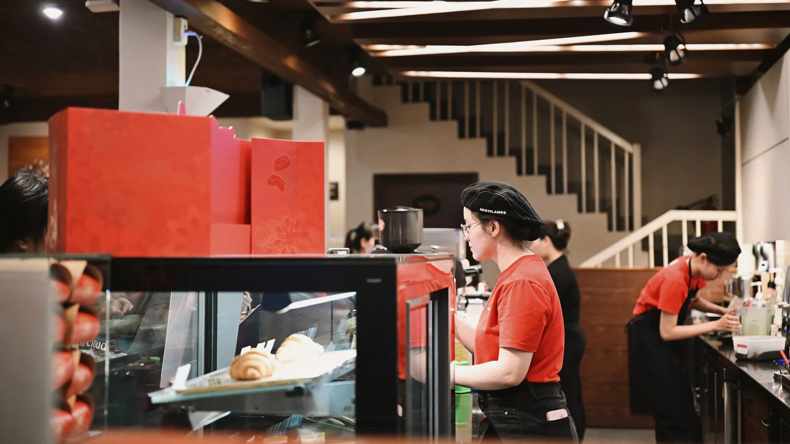Joe & The Juice, la cadena danesa de zumos con Djokovic de socio, abre en Madrid su primera tienda… | ZonaFranquicia Baristas con uniformes rojo preparando bebidas en una cafetería moderna y acogedora con ambiente vibrante | ZonaFranquicia