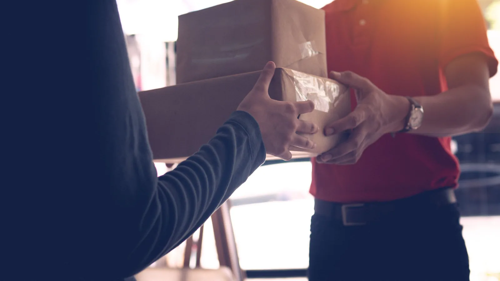 Empleado entregando paquetes a cliente en mostrador de centro de envíos, servicio de atención personalizada | ZonaFranquicia