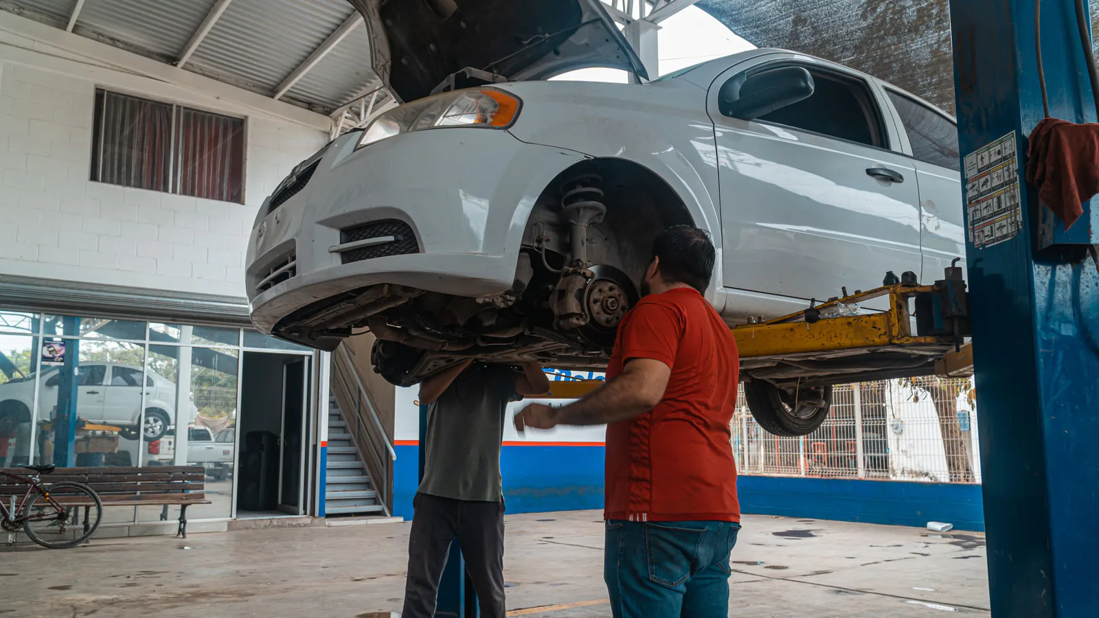 Midas suma su séptimo taller en Canarias con una apertura en La Laguna de la mano de un franquiciad… | ZonaFranquicia Dos mecánicos inspeccionan un automóvil blanco elevado en un taller de reparación profesional | ZonaFranquicia