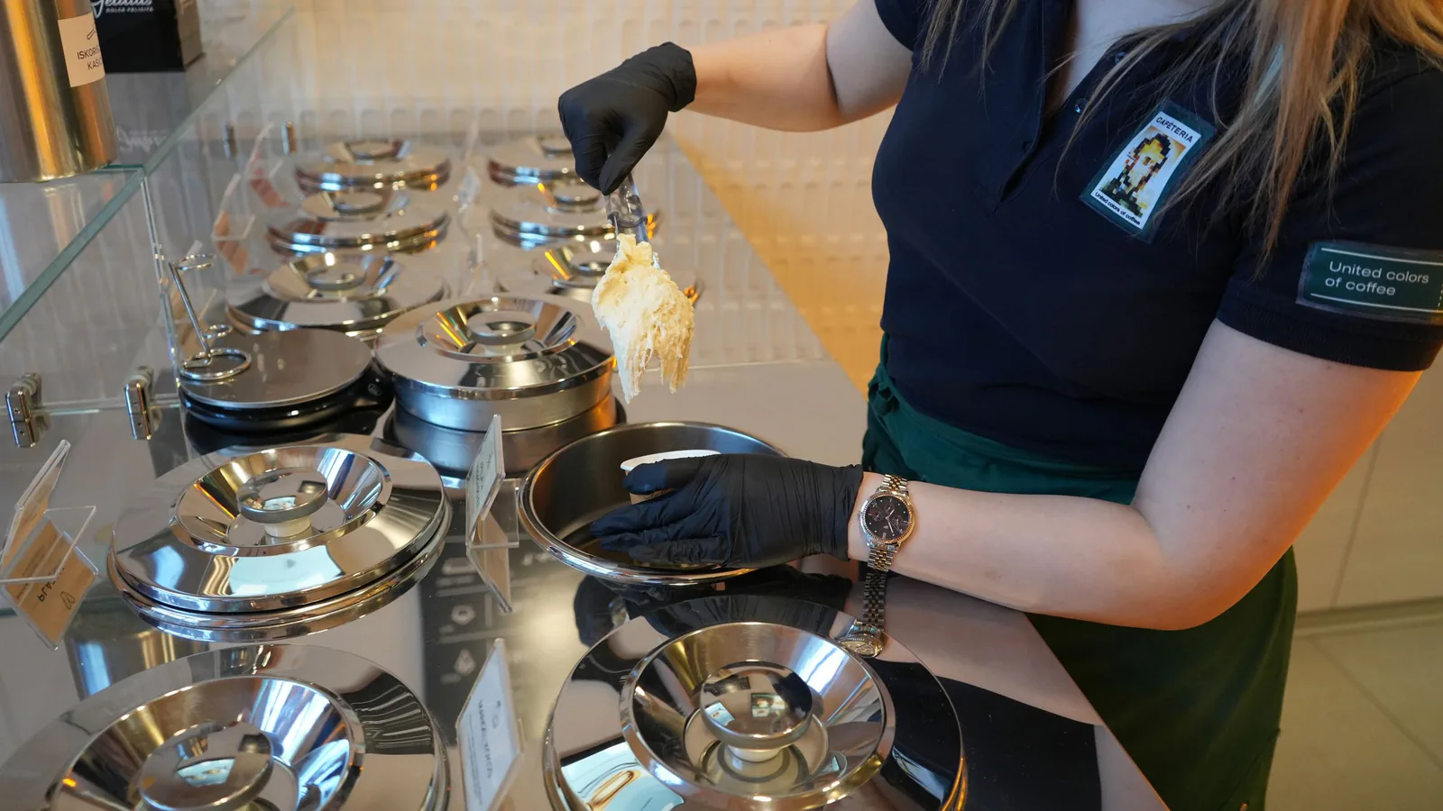 Empleado con uniforme sirve helado con pala en una heladería moderna y luminosa | ZonaFranquicia