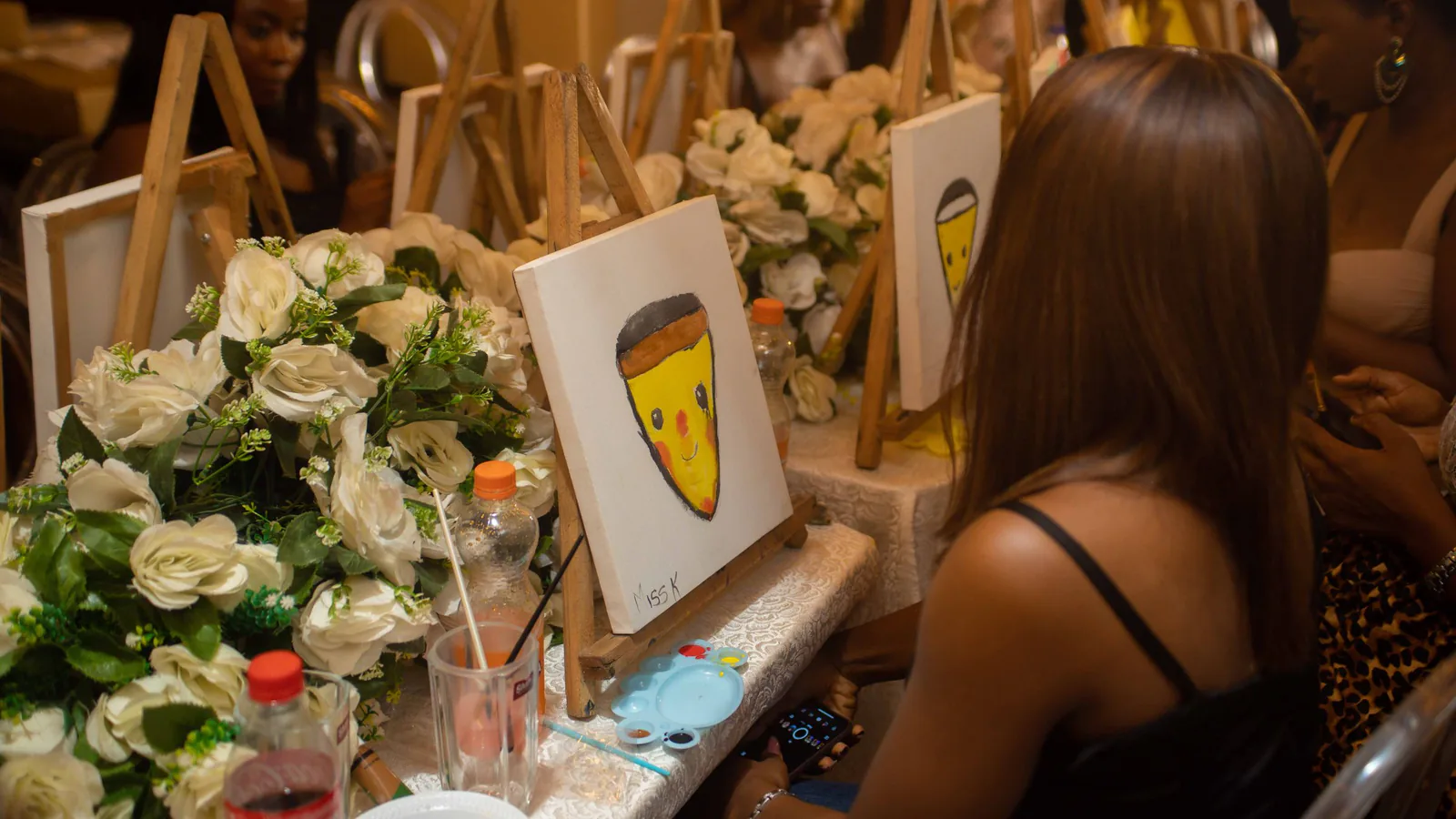 Grupo de mujeres disfrutando de una clase de pintura y vino, pintando lienzos en un ambiente decorado | ZonaFranquicia