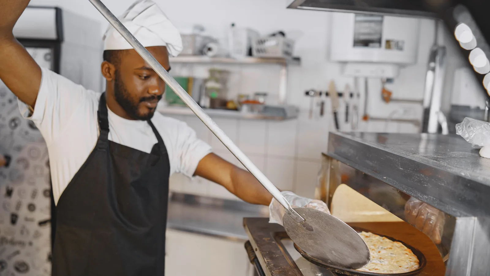 Topepizza sale de Castilla y León: la pizzería artesanal de Valladolid busca franquiciados | ZonaFranquicia Chef colocando pizza fresca en horno de leña tradicional con pala de madera | ZonaFranquicia