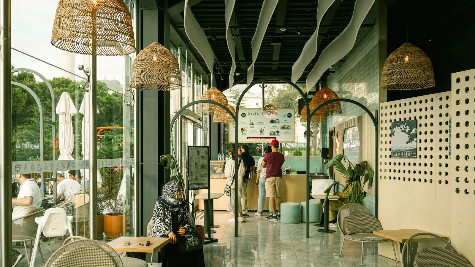 Interior moderno de cafetería con clientes disfrutando en ambiente relajado y diseño contemporáneo | ZonaFranquicia